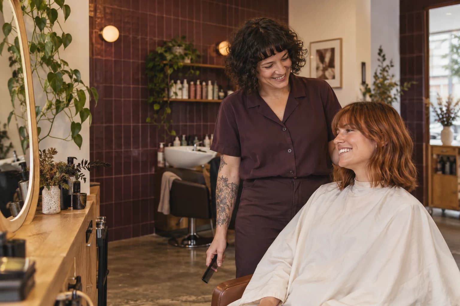 A stylist and her client sharing a laugh after a haircut.